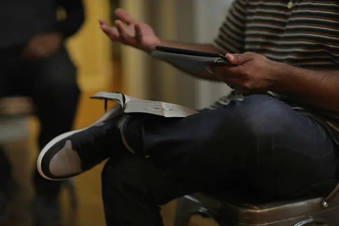 Man sitting with bible on his lap and holding a notebook